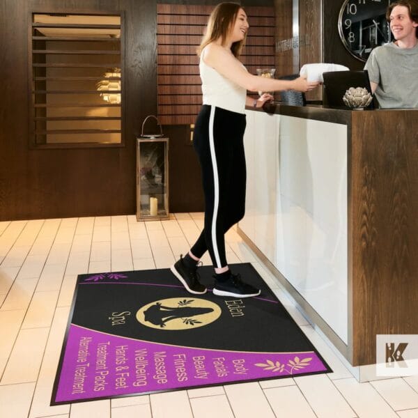 Tapete de entrada personalizado com design circular em preto, dourado e roxo, aplicado numa receção de spa